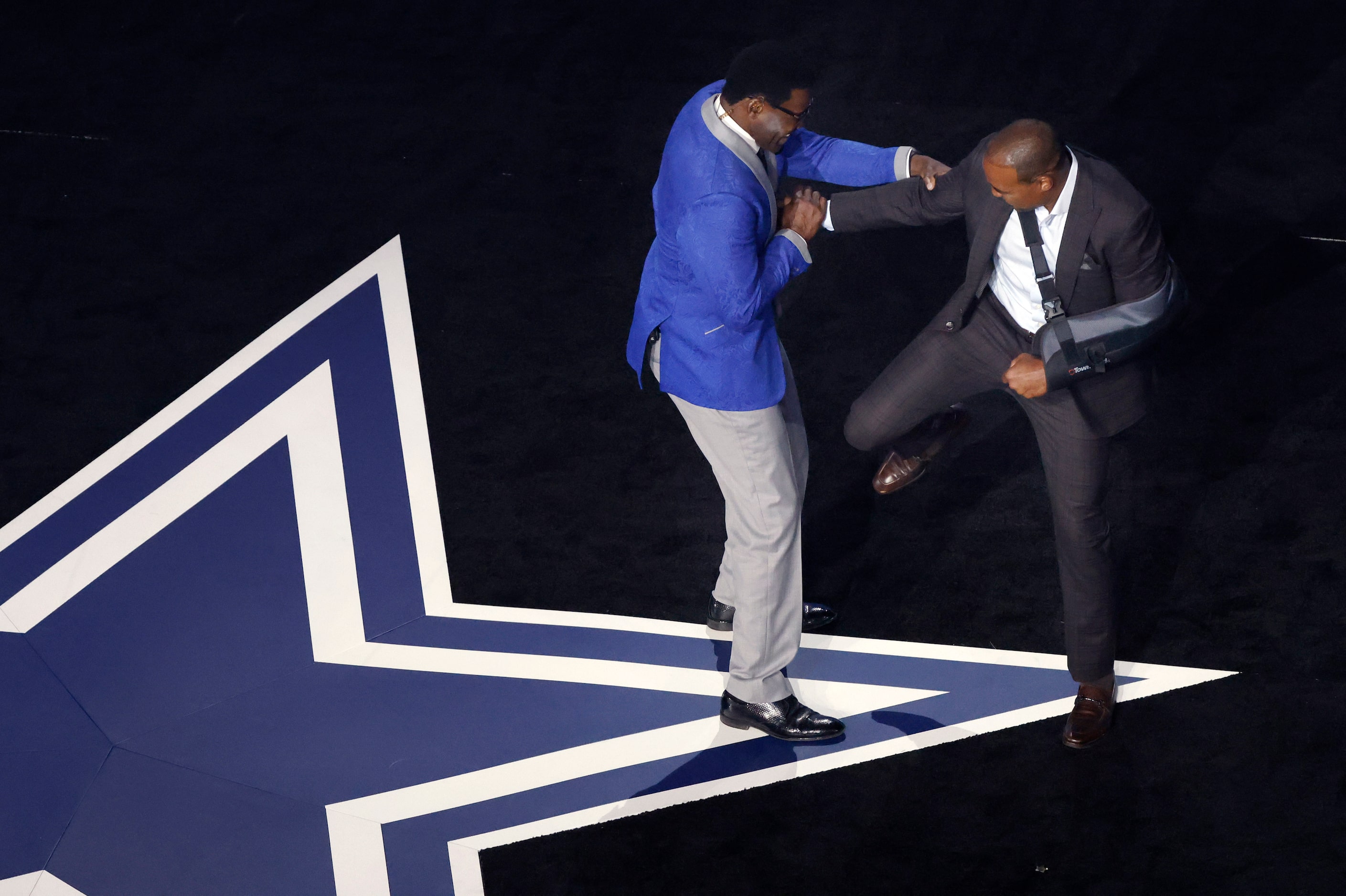 Former Dallas Cowboys players Darren Woodson (right) kicks Michael Irvin after being...