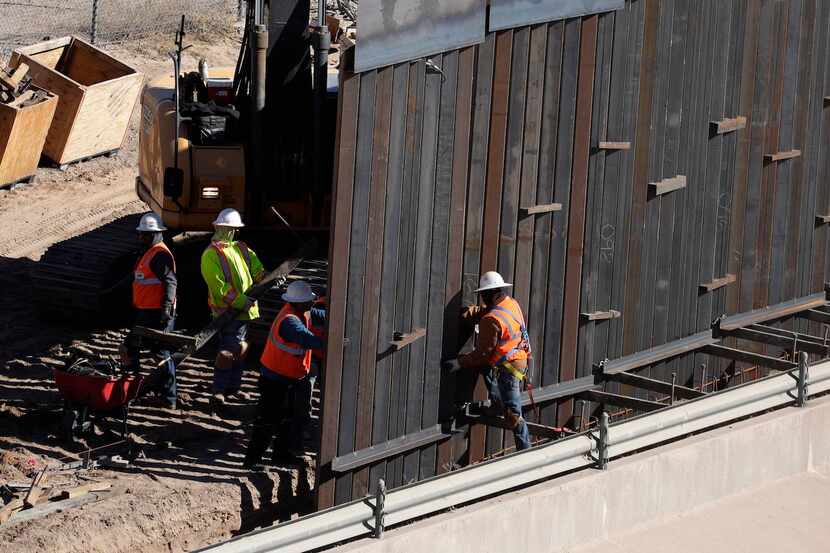 Trabajadores instalar barreras metálicas junto al Río Grande, en la frontera entre El Paso y...