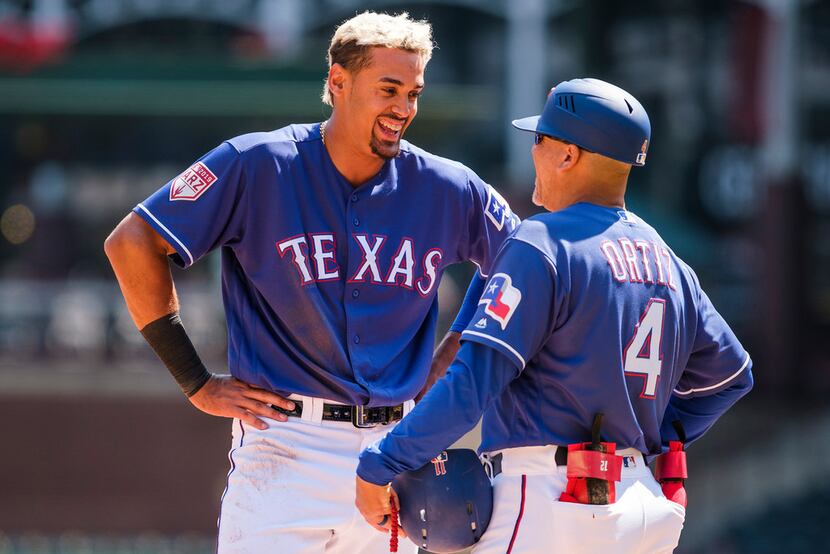 Texas Rangers first baseman Ronald Guzman laughs with first base coach Hector Ortiz after...