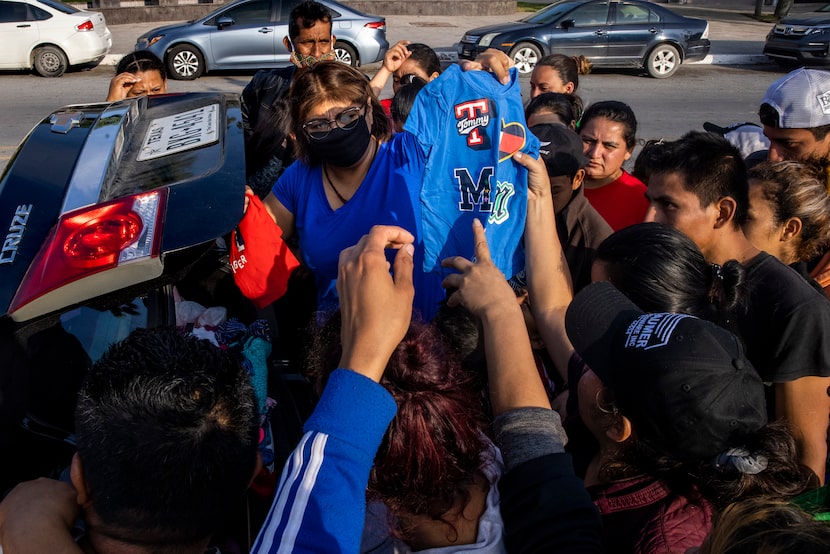 Violeta Aparicio, center, donates clothes and other goods to expelled migrants who have set...