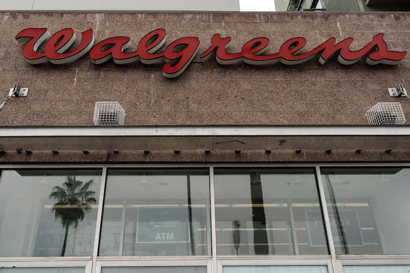 A palm tree is reflected in the window of a Walgreens pharmacy in Los Angeles, Friday, March...