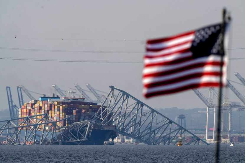 A U.S. flag flies on a moored boat as the container ship Dali rests against the wreckage of...
