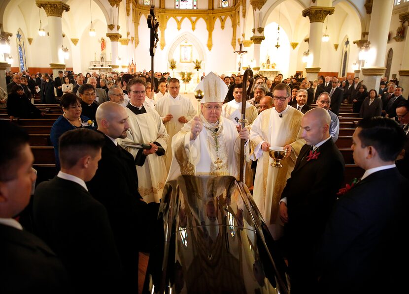 Bishop Kevin J. Farrell sprinkles Holy Water on the casket before leading a funeral mass for...