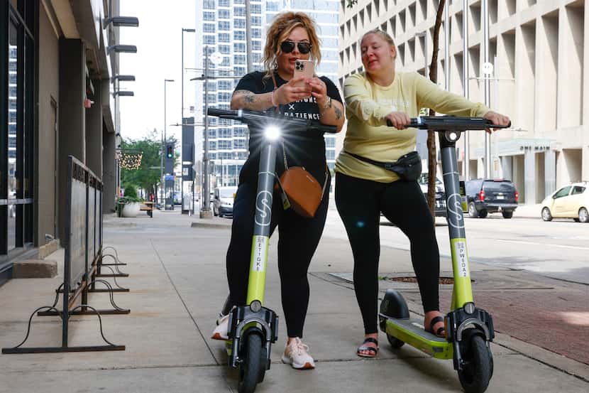 Two electric scooter riders in downtown Dallas in May 2023.