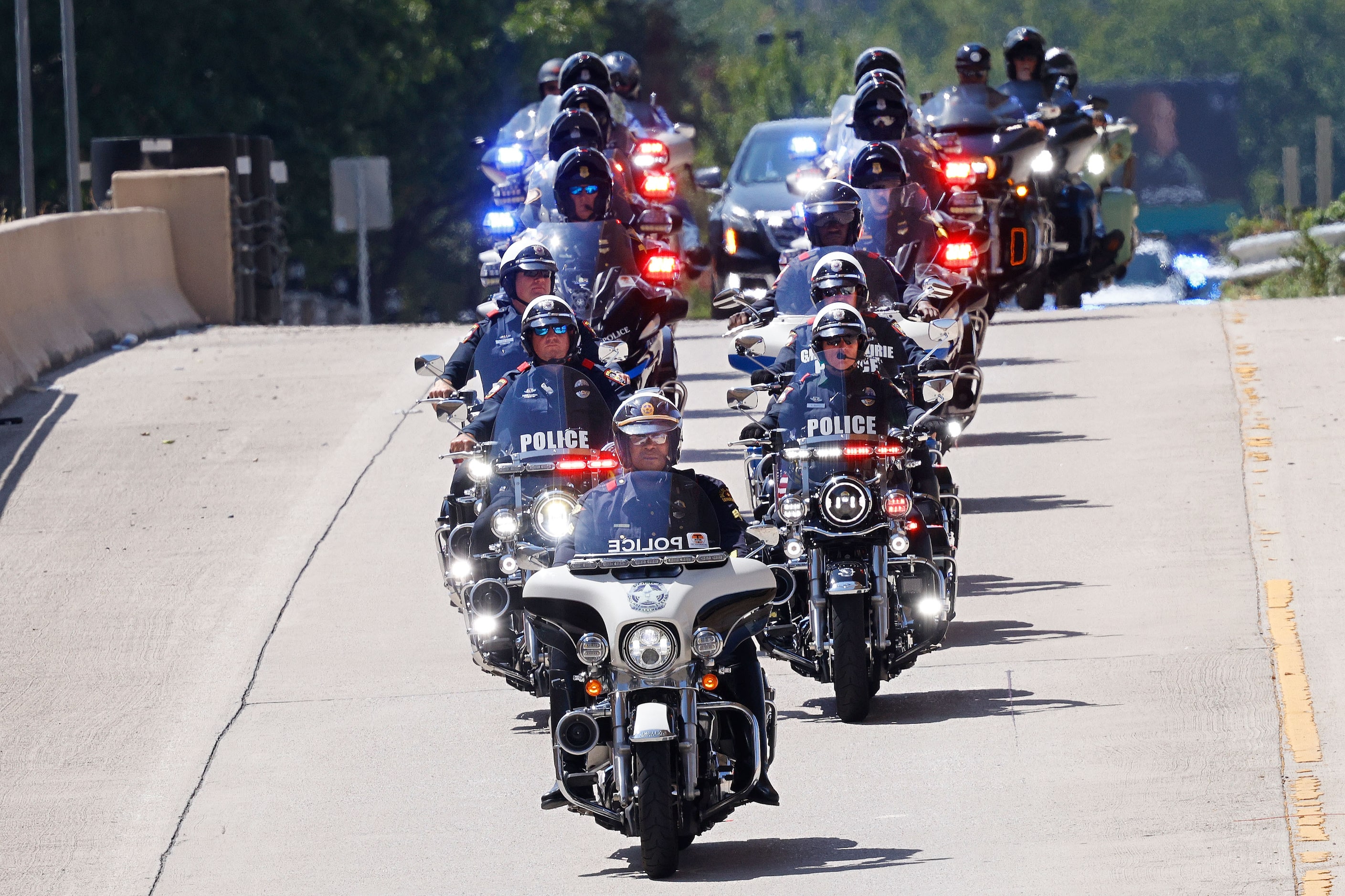 Police motorcycles lead the procession carrying the body of Dallas police officer Darron...