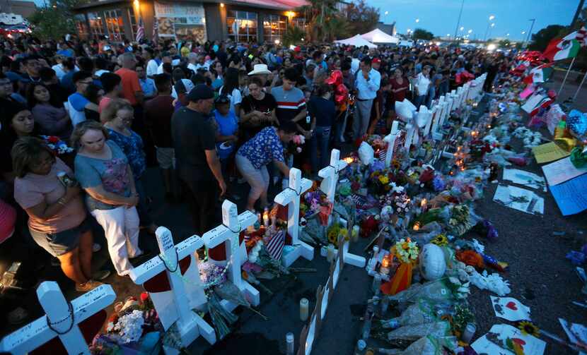 People stand next to 22 crosses at the site of a makeshift memorial for victims of the mass...