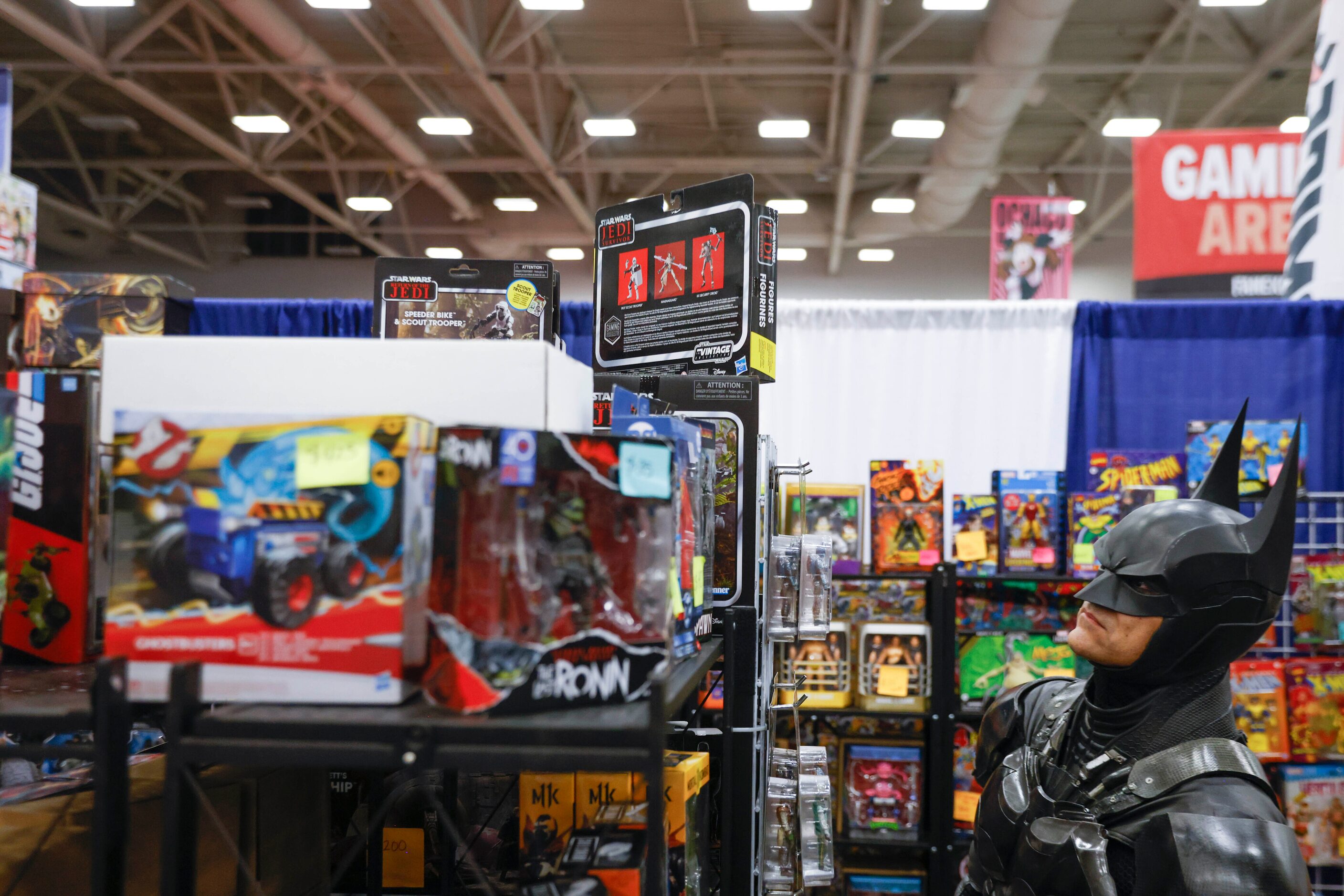 Will Ellis dressed as Batman looks to buy an action figure during Fan Expo Dallas on Friday,...