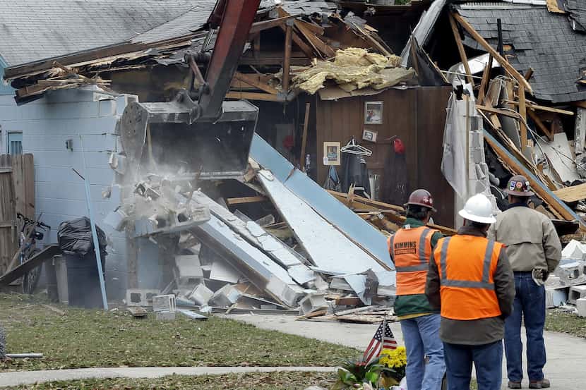 Demolition experts watch as the home of Jeff Bush, 37,  is destroyed Sunday, March 3, 2013,...