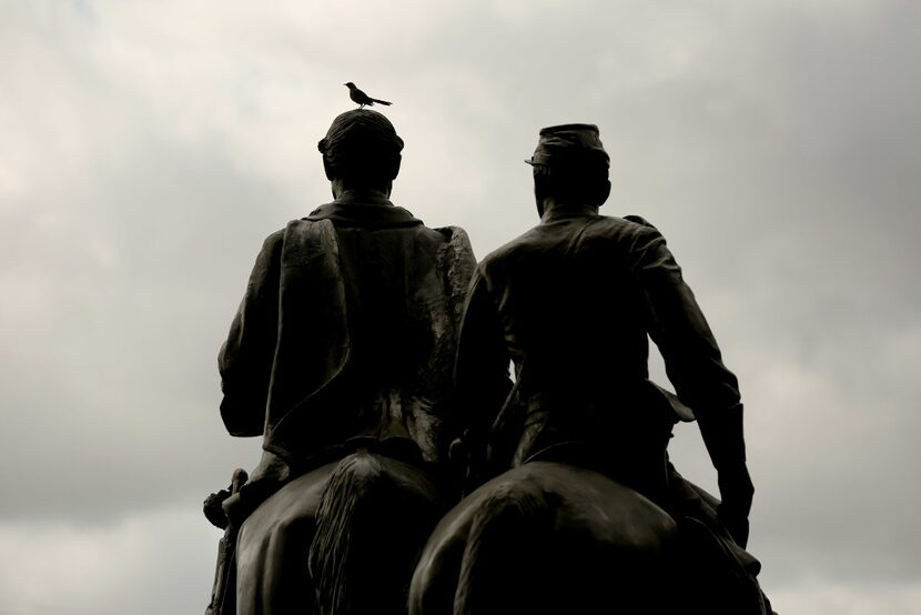 A bird sits atop a statue of Confederate general Robert E. Lee at Robert E. Lee Park in the...