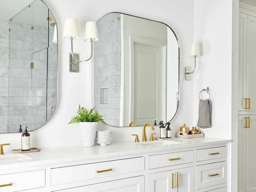 A bathroom features white cabinetry with gold hardware.