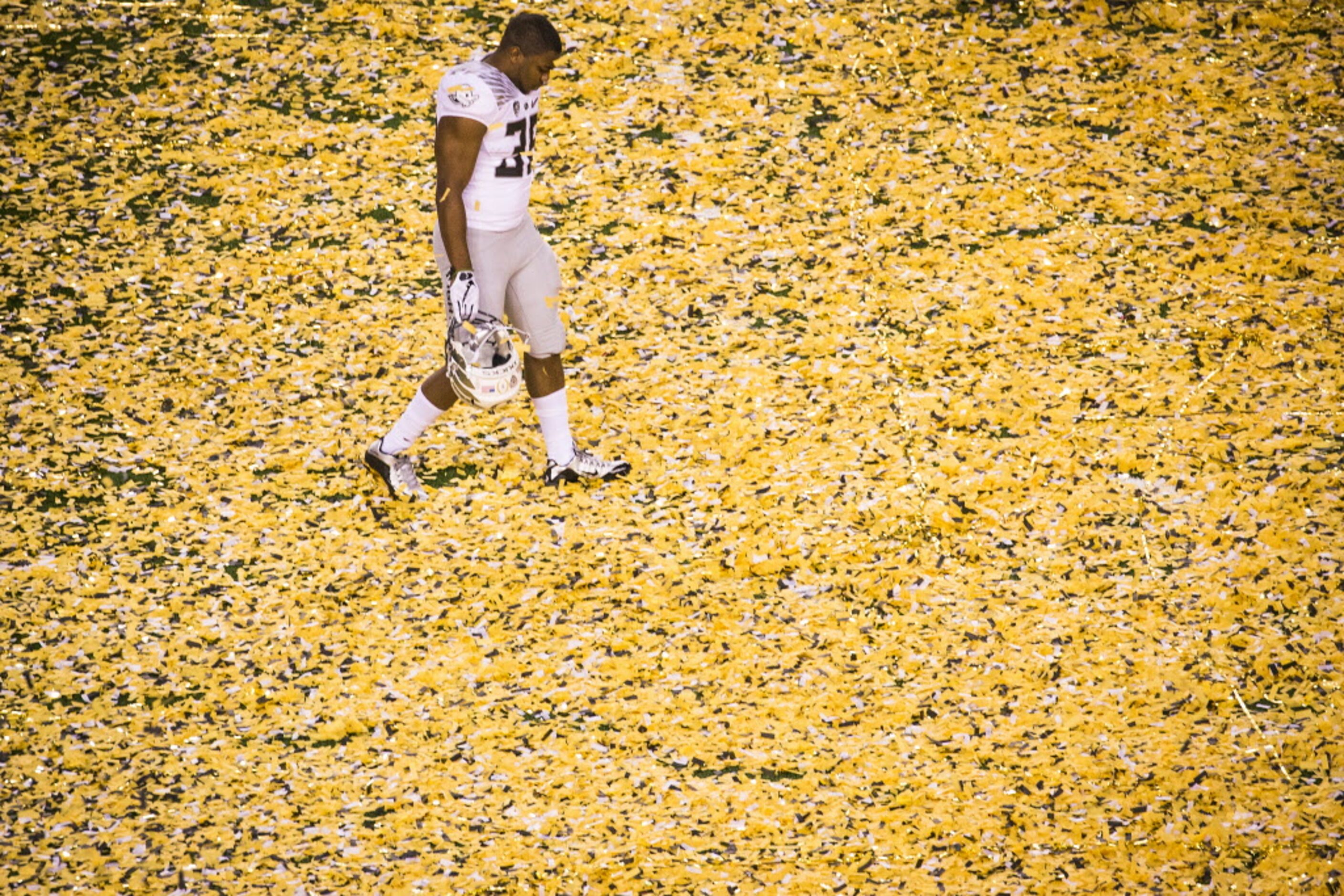 Oregon Ducks running back Kani Benoit walks off the field through a blanket of confetti...