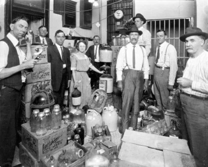 Law enforcement officers stand in a room containing confiscated bootleg liquor during...