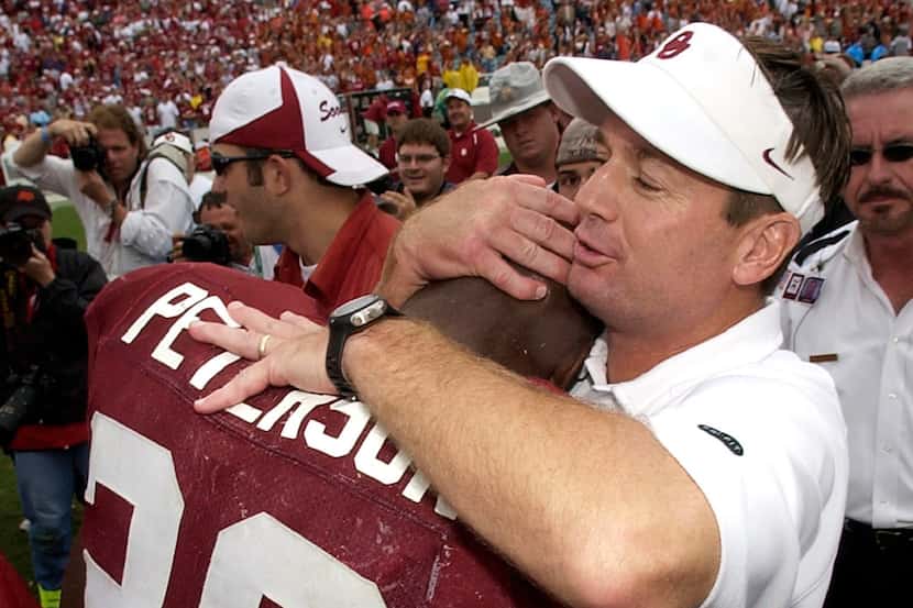 FILE - In this Oct. 9, 2004, file photo, Oklahoma coach Bob Stoops hugs running back Adrian...