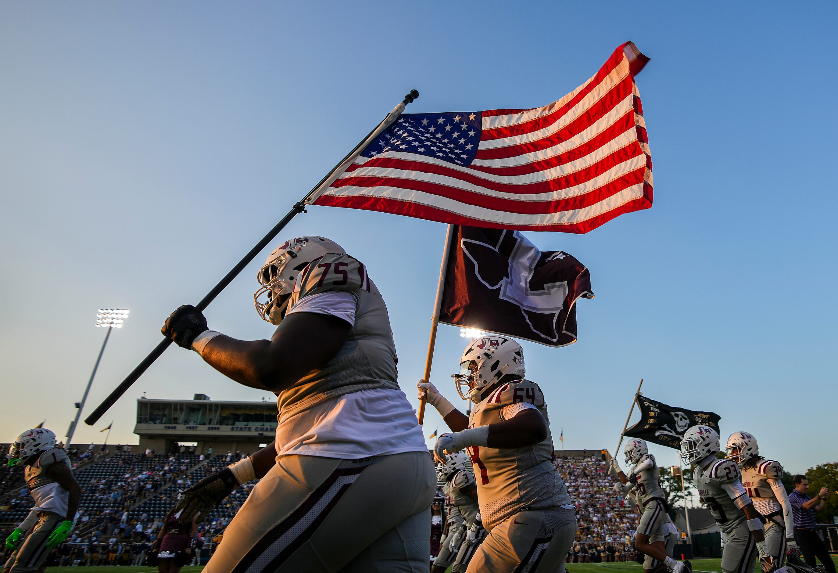 Lewisville offensive lineman Xavion Davis (75) carries the American flag as the team takes...