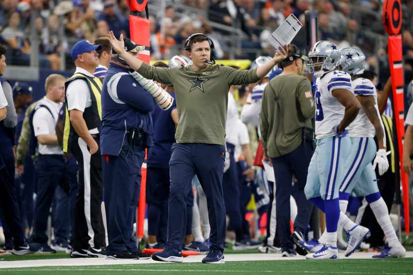 Dallas Cowboys offensive coordinator Kellen Moore gestures with his arms as he watches play...