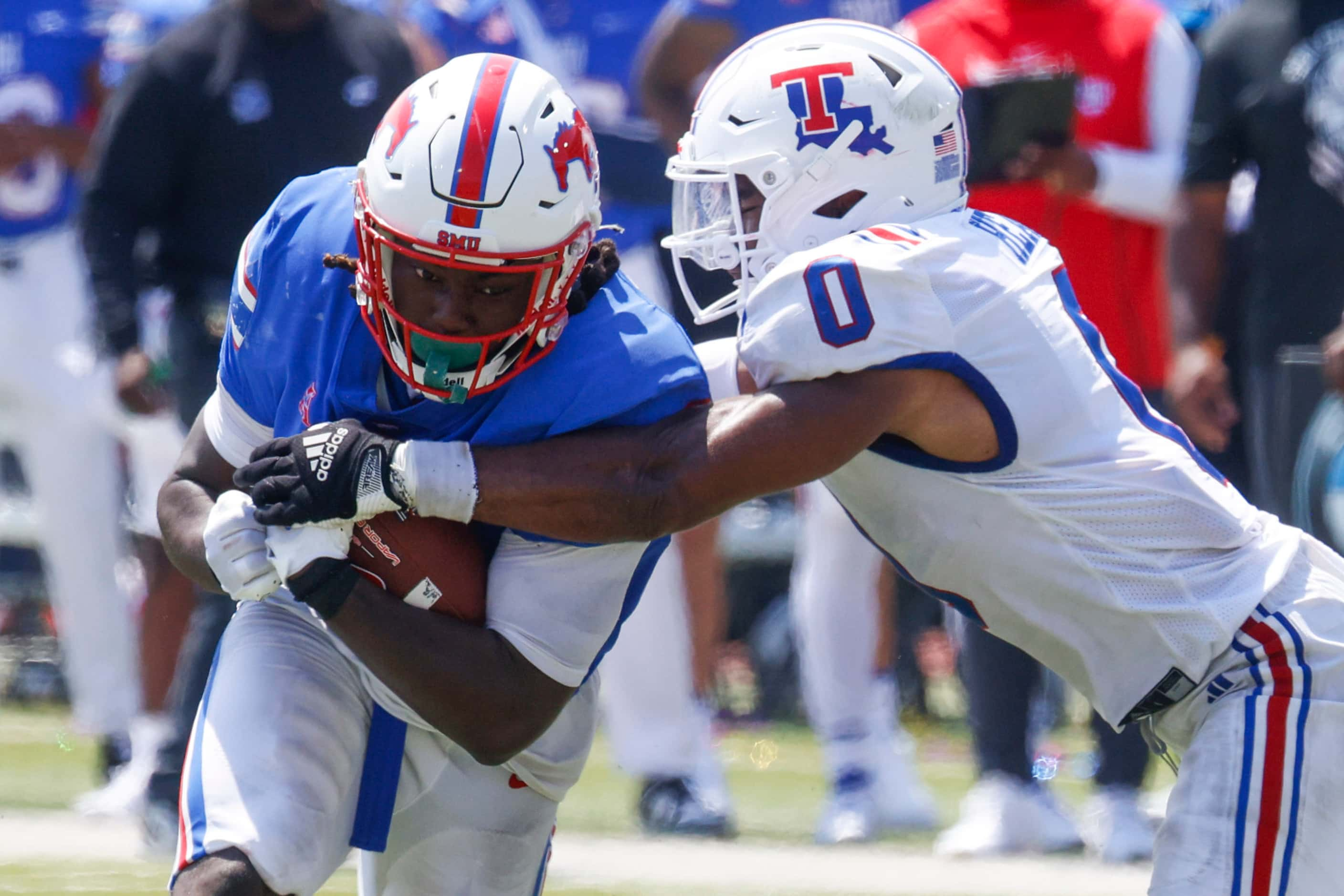 Southern Methodist running back LJ Johnson Jr. (left) gets tackled by Louisiana Tech...