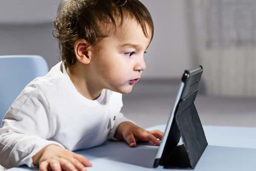 Un niño pequeño mira atentamente la pantalla de una tablet. iSTOCK.
