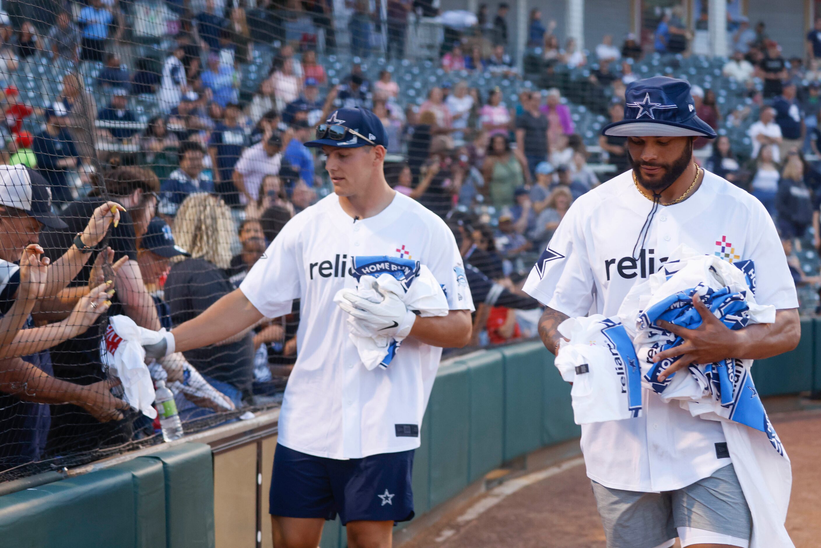 Dallas Cowboys QB Dak Prescott (right) and linebacker Leighton Vander Esch give t-shirts to...