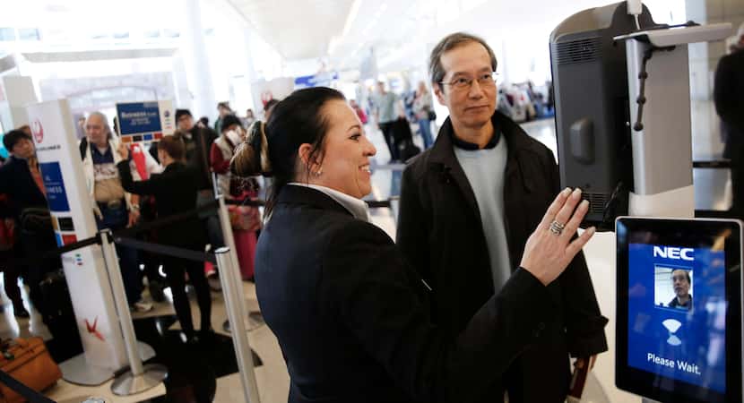 Sylvia Johnson, a customer service agent with Japan Airlines, helps a passenger use new...