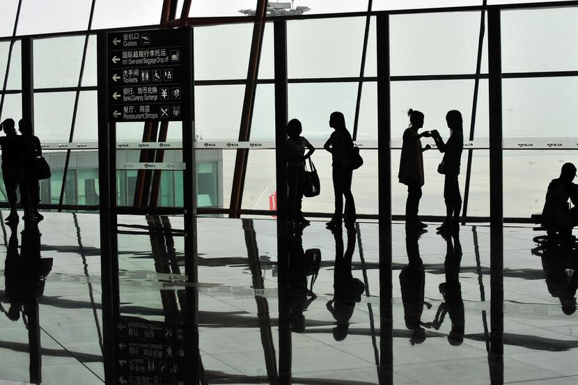 Travelers look out of a window in Beijing Capital International Airport. A.O. Smith, one of...