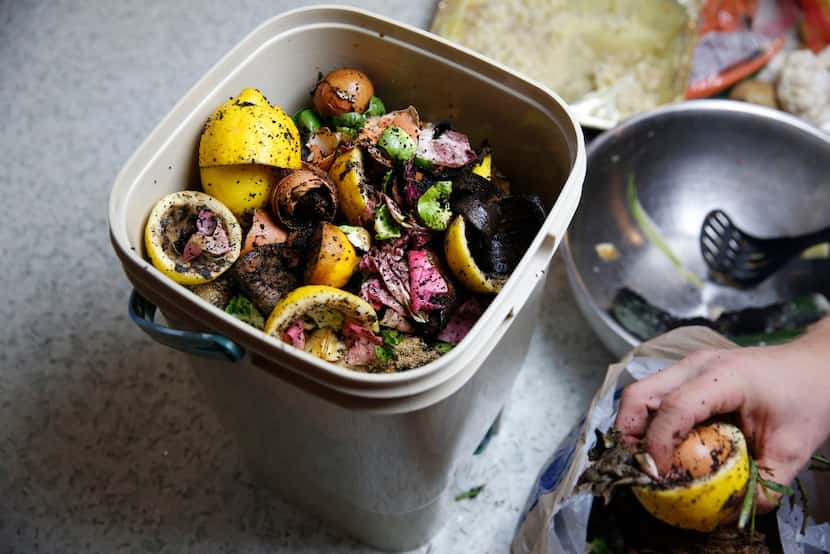 Horticulturist Daniel Cunningham puts in a layer of food scraps to make compost inside a...