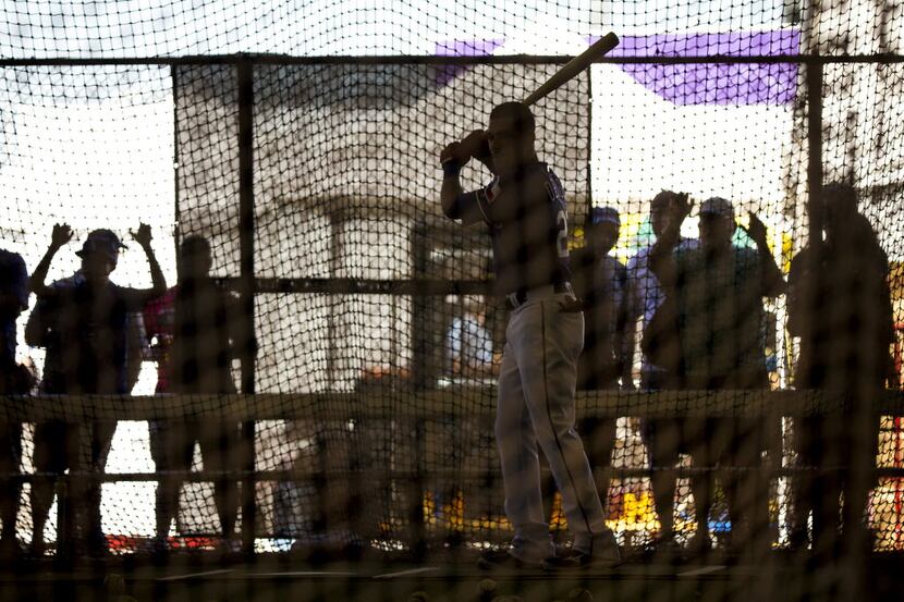 Fans press against a fence to watch Texas Rangers outfielder Ian Desmond take batting...