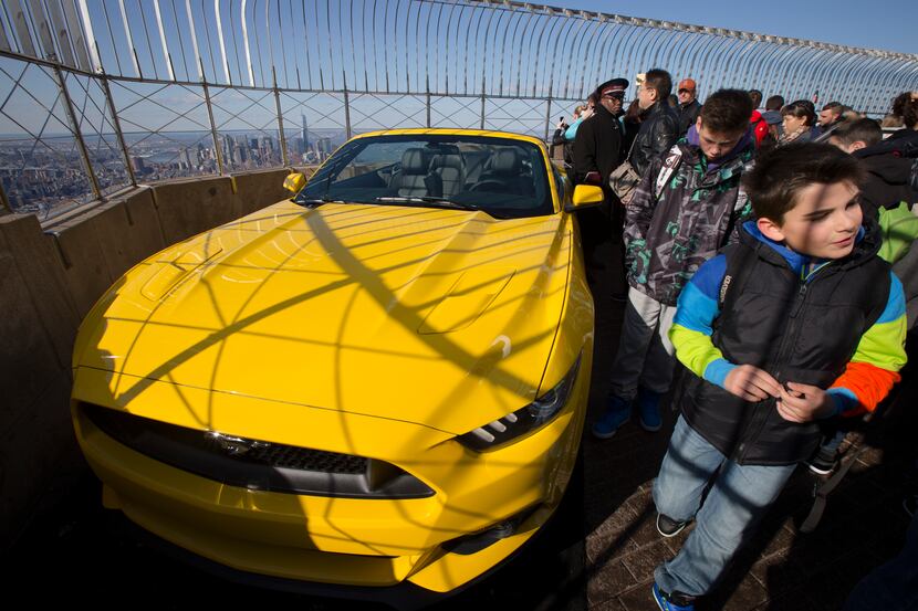 People walk past the all-new 2015 Mustang convertible as it's revealed by the Ford Motor...