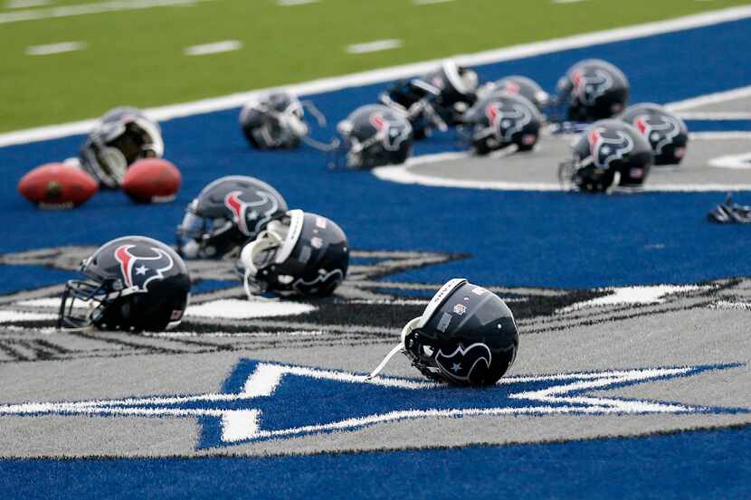 Several Houston Texans helmets sit over the Dallas Cowboys logo in the end zone as the...