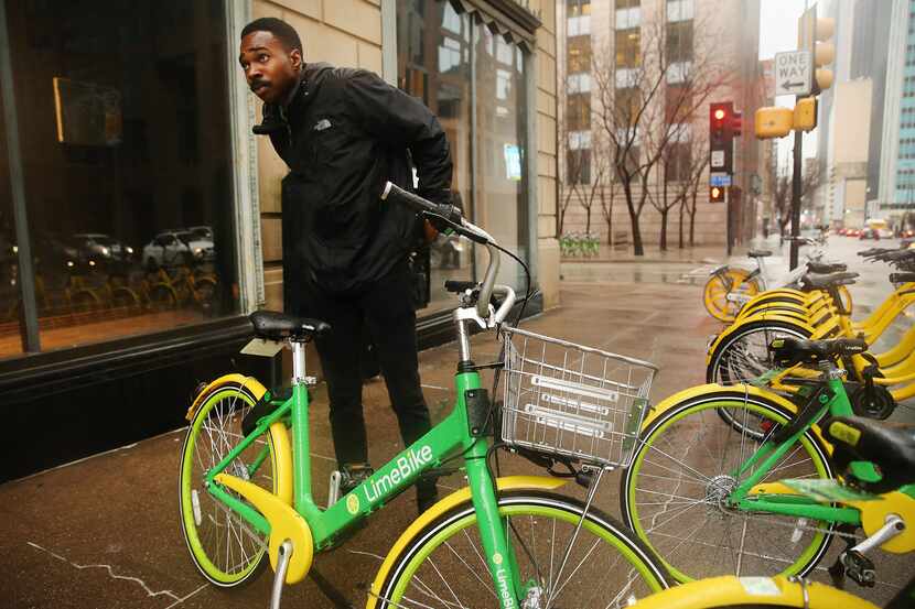 Christian Scull, a lead and operations specialist, rebalances LimeBike bicycles in downtown...