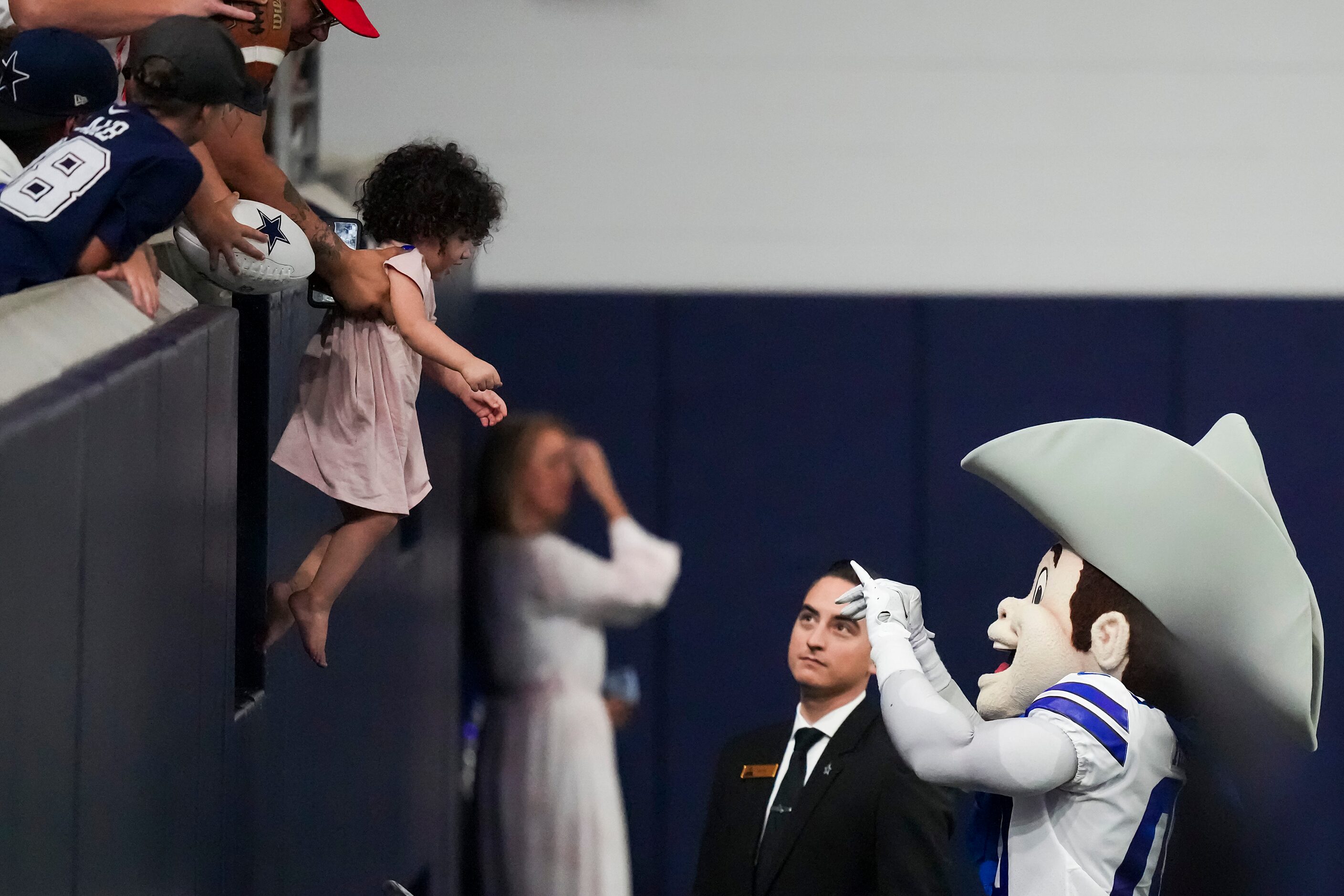 A fan holds a child out toward Dallas Cowboys mascot Rowdy before the opening ceremony for a...