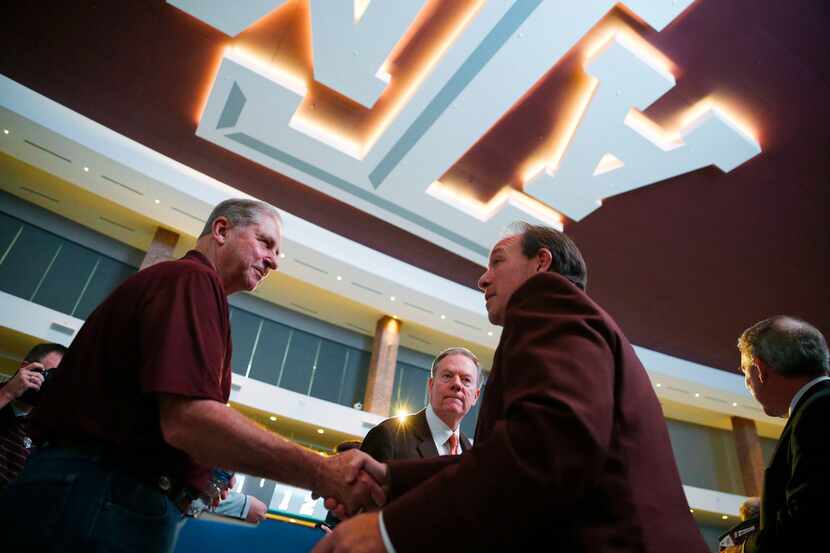 Texas A&M's new coach Jimbo Fisher (right) shakes hands with fans after a press conference...