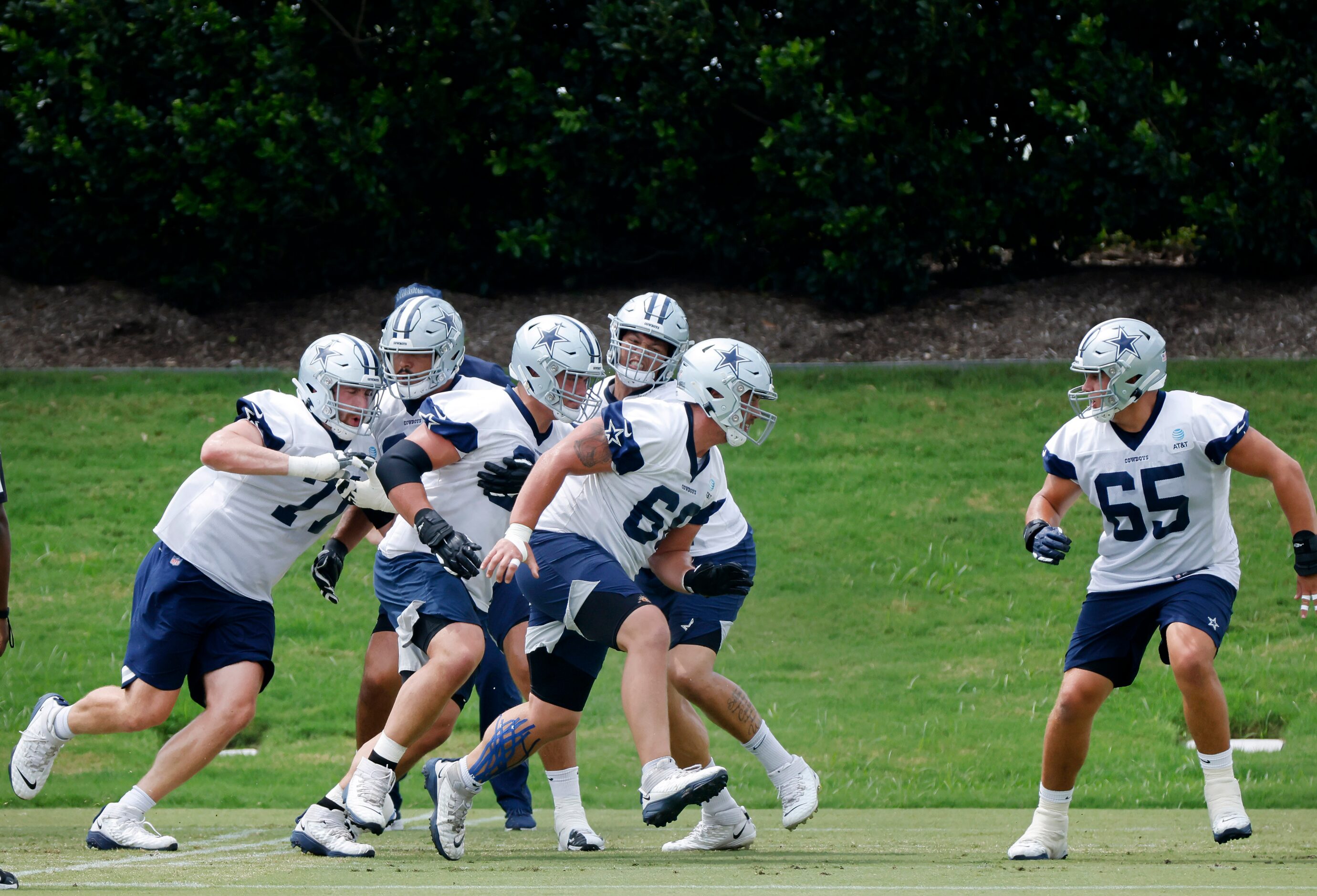 The offensive line works on blocking drills during training camp practice at The Star in...