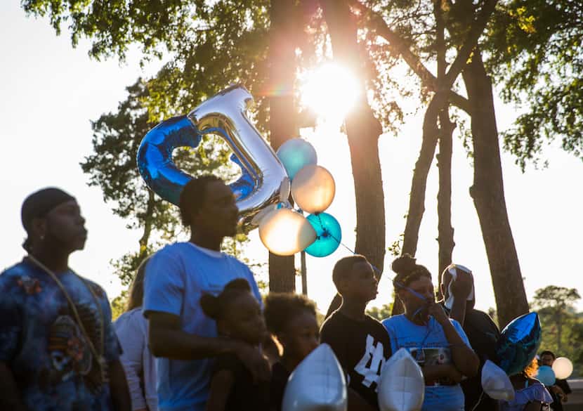 Friends and family members hold balloons during a vigil for 18-month-old Cedrick "C.J."...