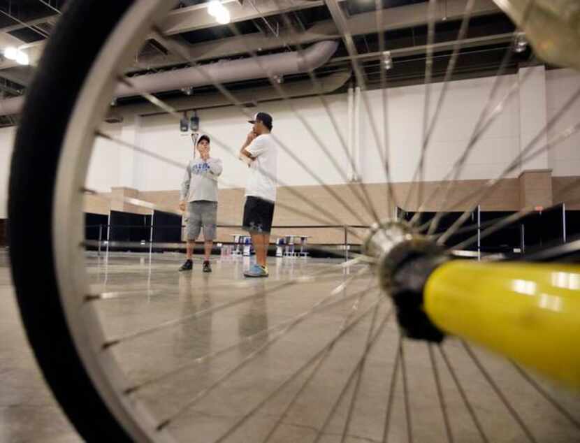 
Framed by the wheel of a hand cycle, Paul Gray (left), founder of RISE Adaptive Sports, and...