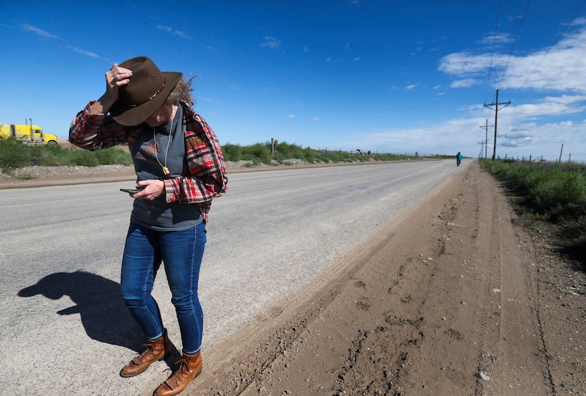 Sharon Wilson holds her hat down against the wind gusts while taking emissions readings. 