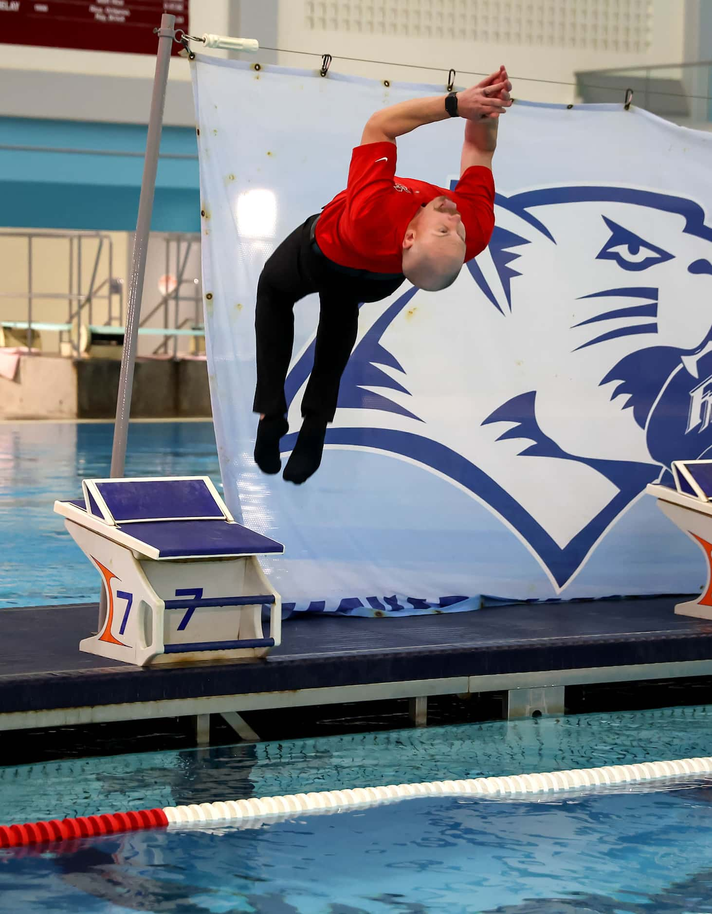 Flower Mound Marcus head coach Brandon Dion does a back flip into the pool after their...