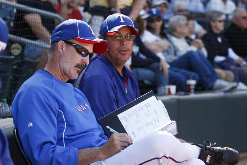 Texas Rangers pitching coach Mike Maddux, left, makes notes while sitting next to his...