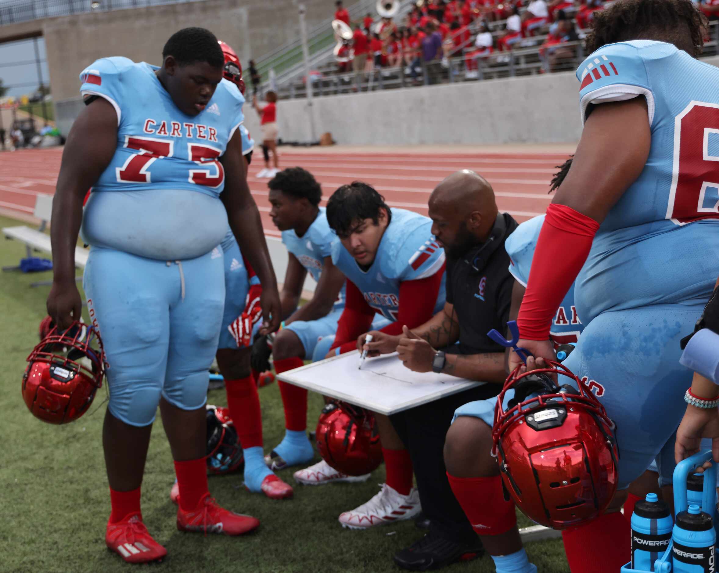 A Dallas Carter assistant coach goes over game strategy with players on the team sideline...