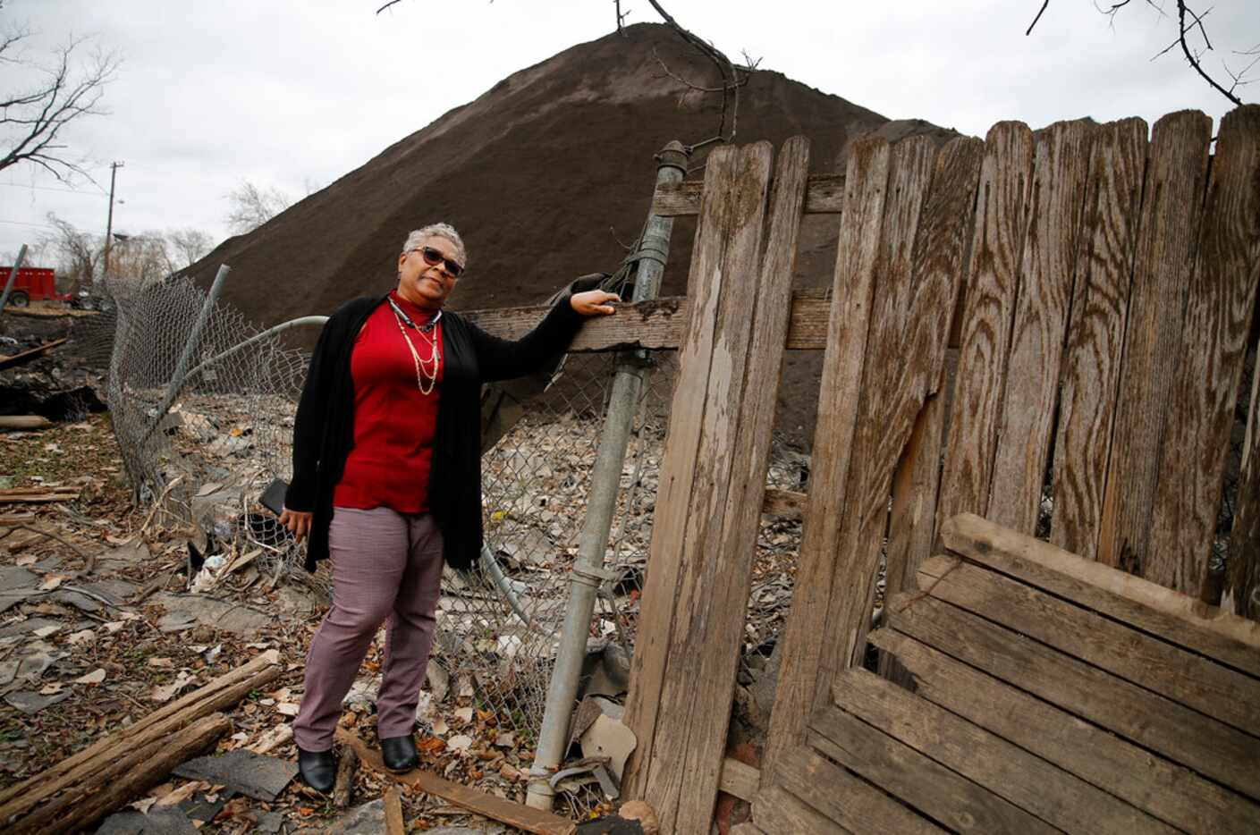 Homeowner Marsha Jackson looks over her damaged fence at the large mounds of shredded...