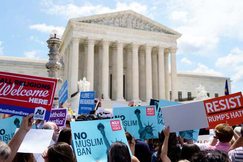 Protesters hold up signs and call out against the Supreme Court ruling upholding President...