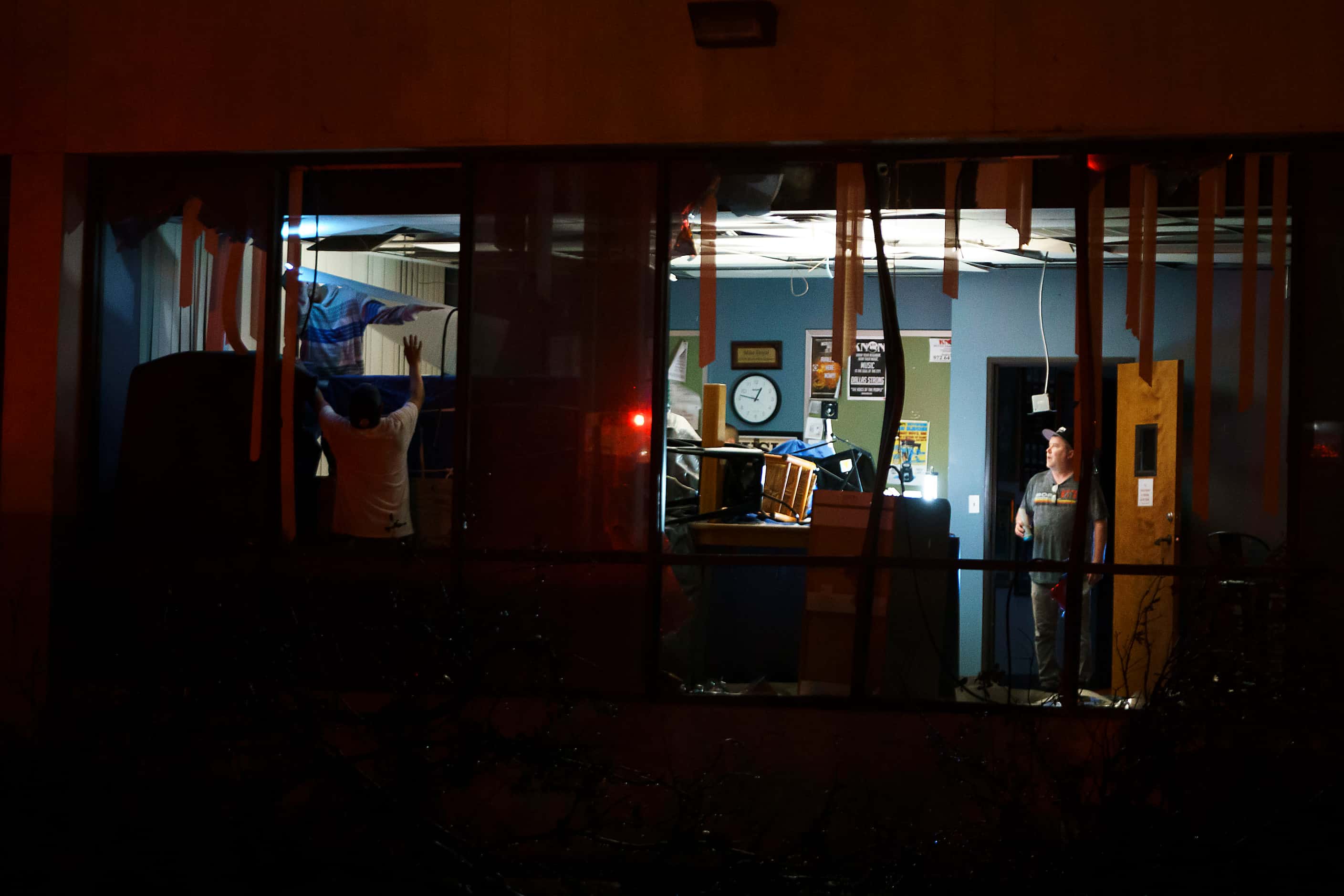 People pick through tornado damage to an office building near the intersection on North...