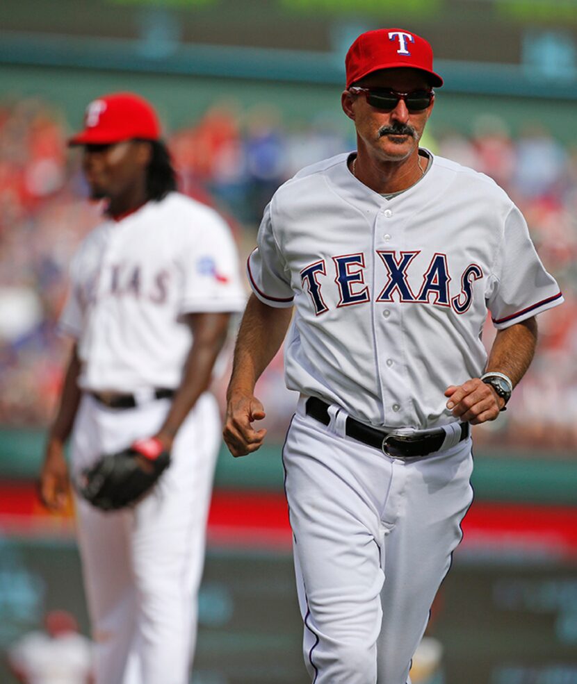  Texas Rangers pitching coach Mike Maddux (31) is pictured leaving the field after talking...