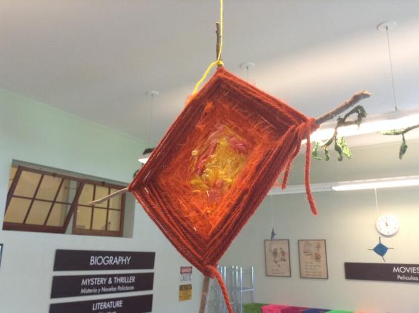 
Variations of the God’s eye, a yarn-weaving craft, are suspended from overhead fixtures. 
