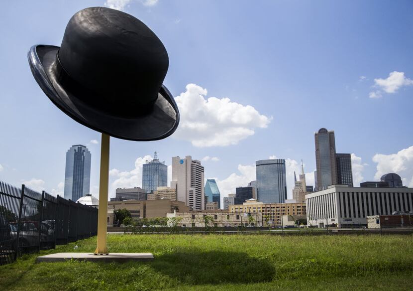 A sculpture of a giant bowler hat by Keith Turman is seen with the Dallas skyline behind it...