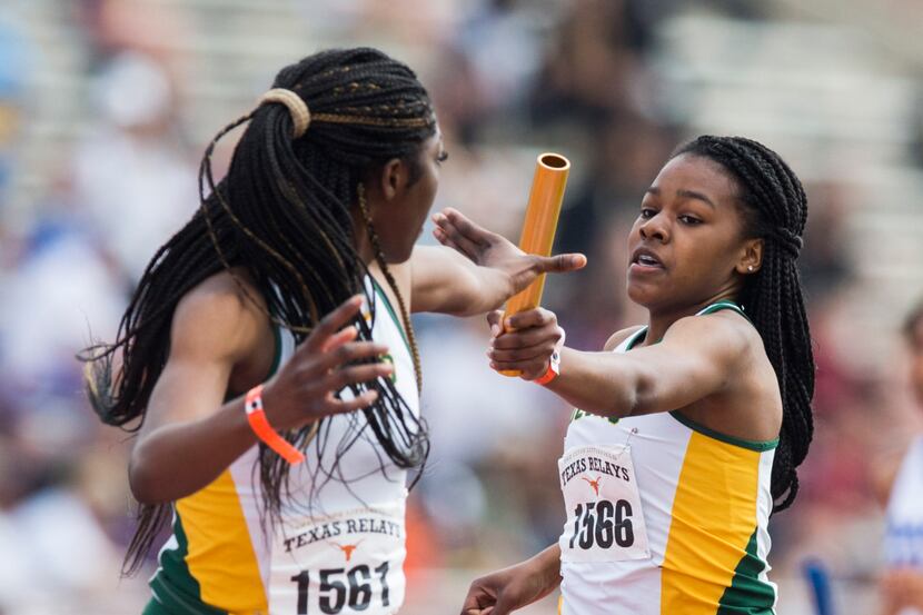 DeSoto’s Trinity Kirk (right) hands off the baton to Rosaline Effiong (left) during the High...