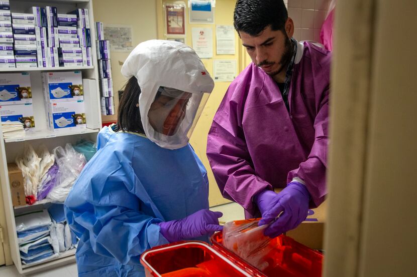 Microbiologists Agnes Marfo and Juan Jaramillo review and log COVID-19 test kits at the...