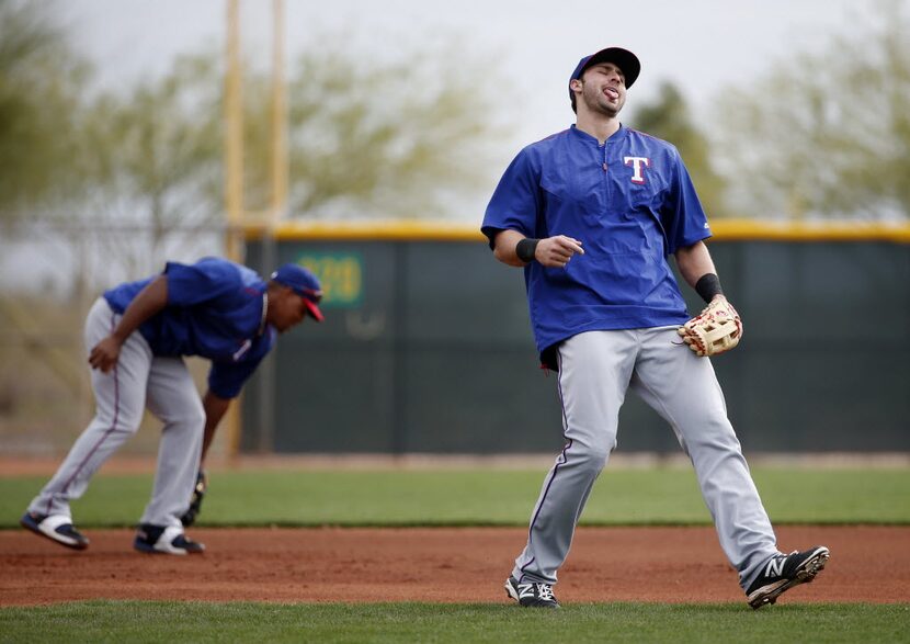 Texas Rangers infielder Joey Gallo reacts to misplaying a ball hit to him at third base...