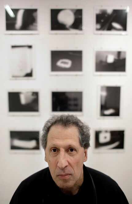Photographer Karl Baden, of Cambridge, Mass., sits for a photo in front of an exhibit of his...