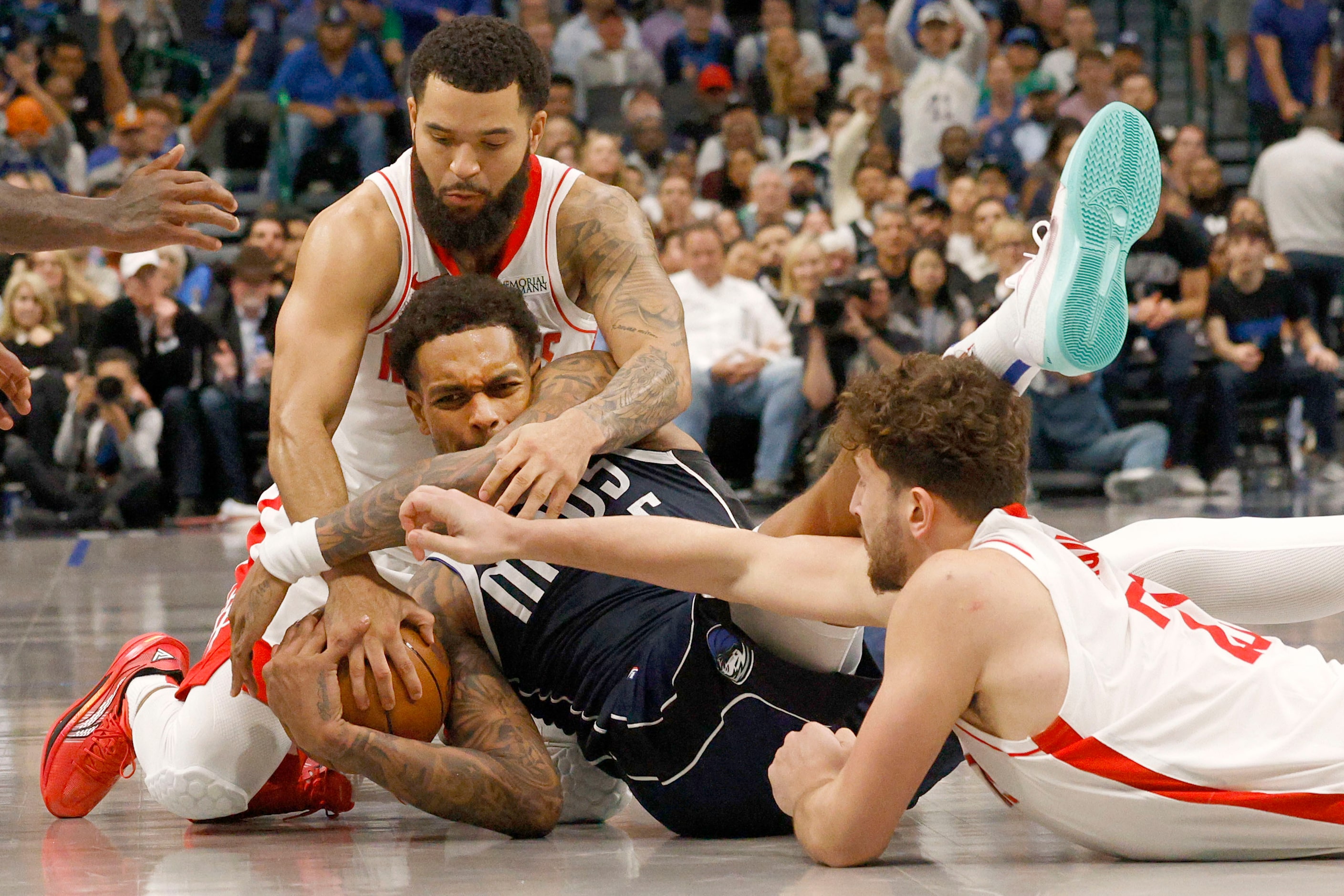 Dallas Mavericks forward P.J. Washington (25), center, keeps the ball away from Houston...