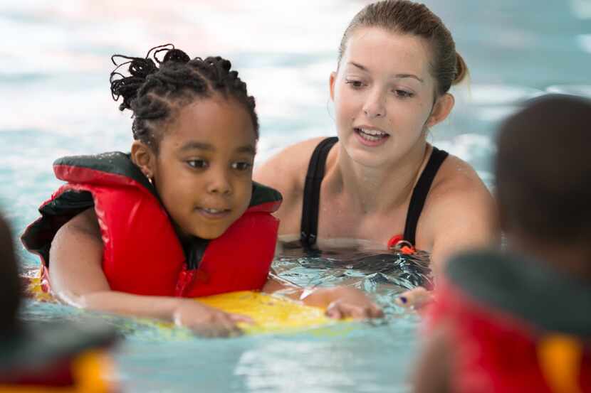 A woman teaches a little girl how to swim.